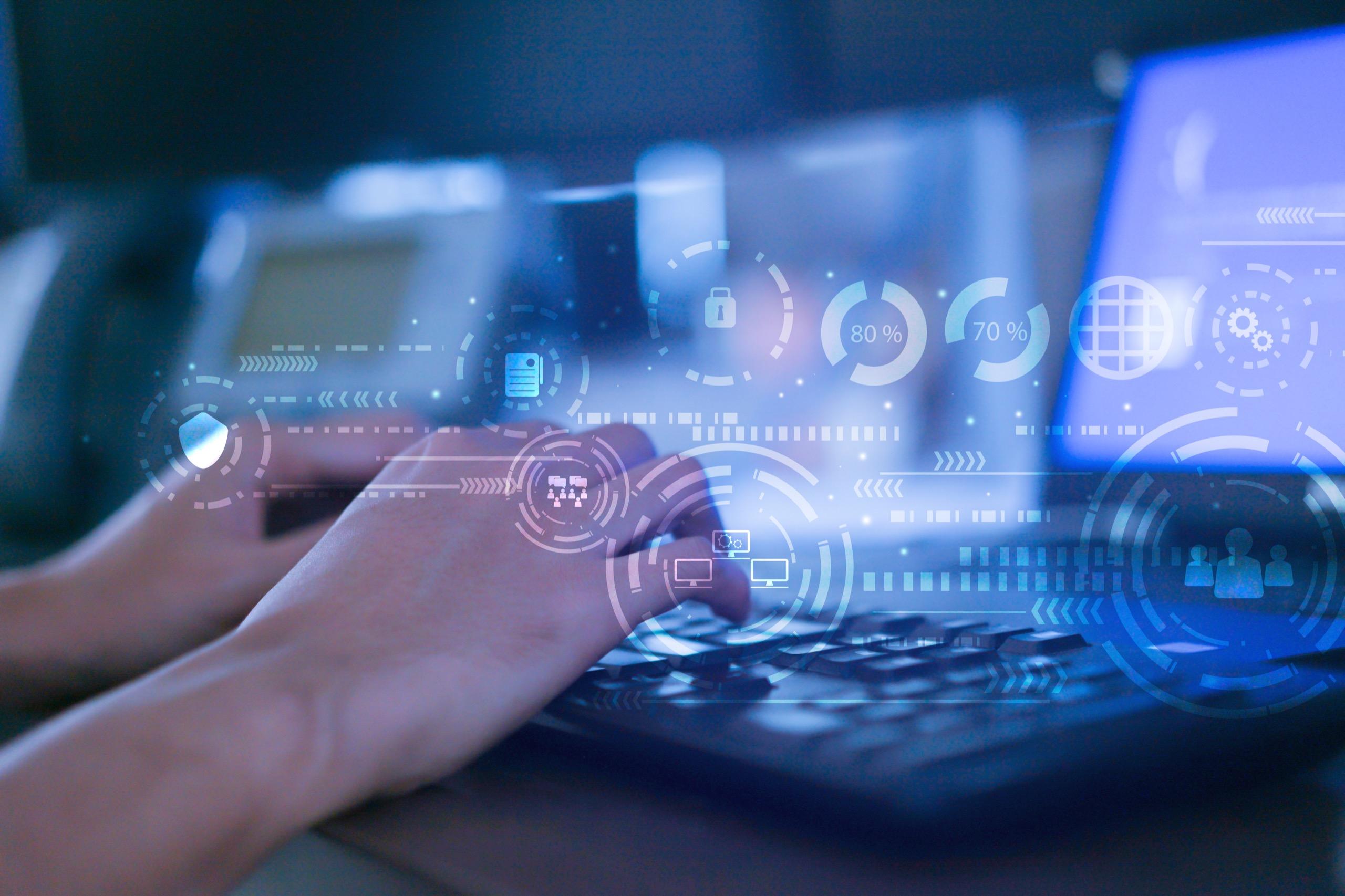 Hands typing on a keyboard with digital data overlay, representing integrated digital solutions and smart facilities management systems.