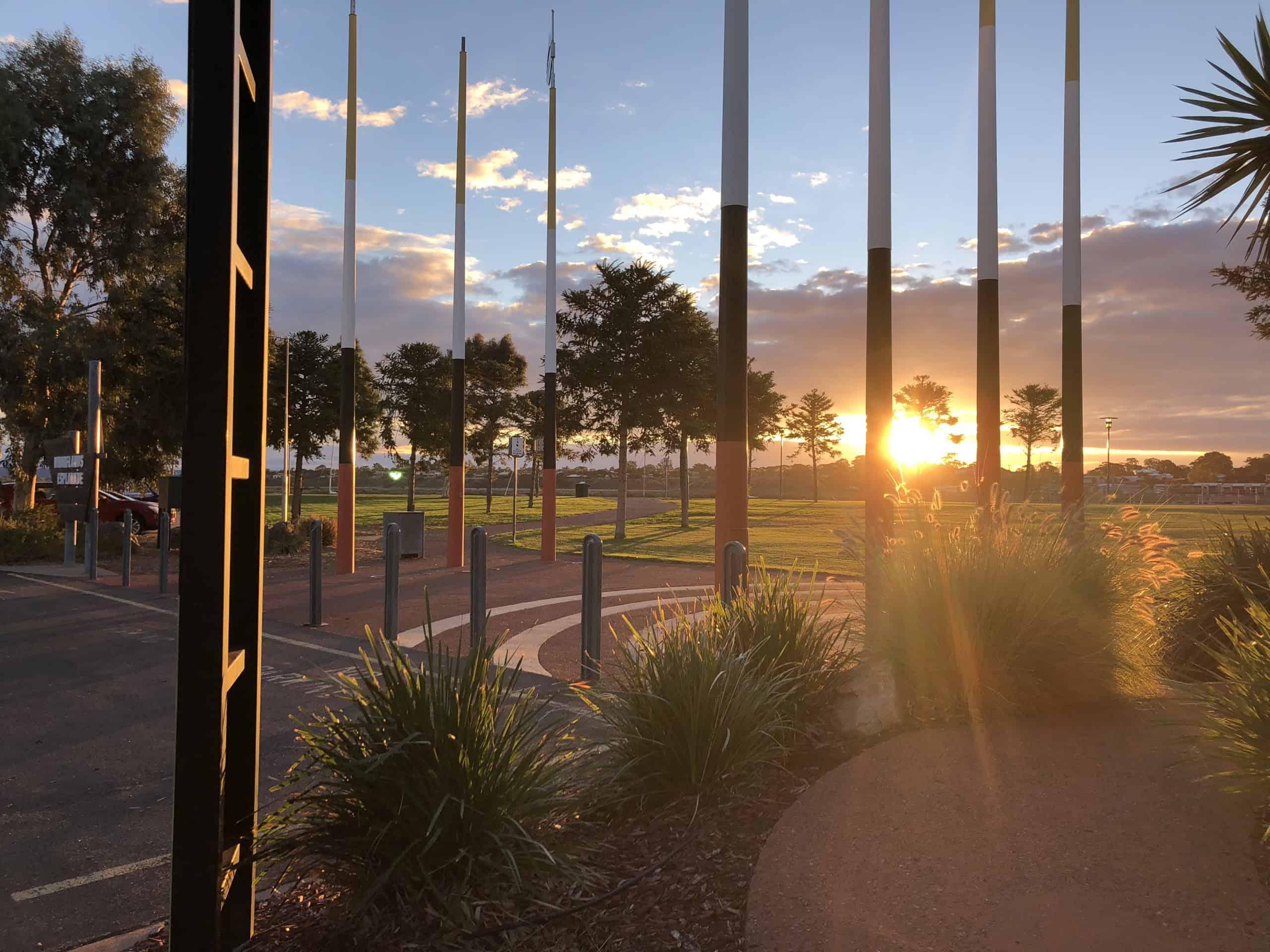 A group of people enjoying an outdoor community event at sunset, with city buildings in the background, highlighting local government collaboration.