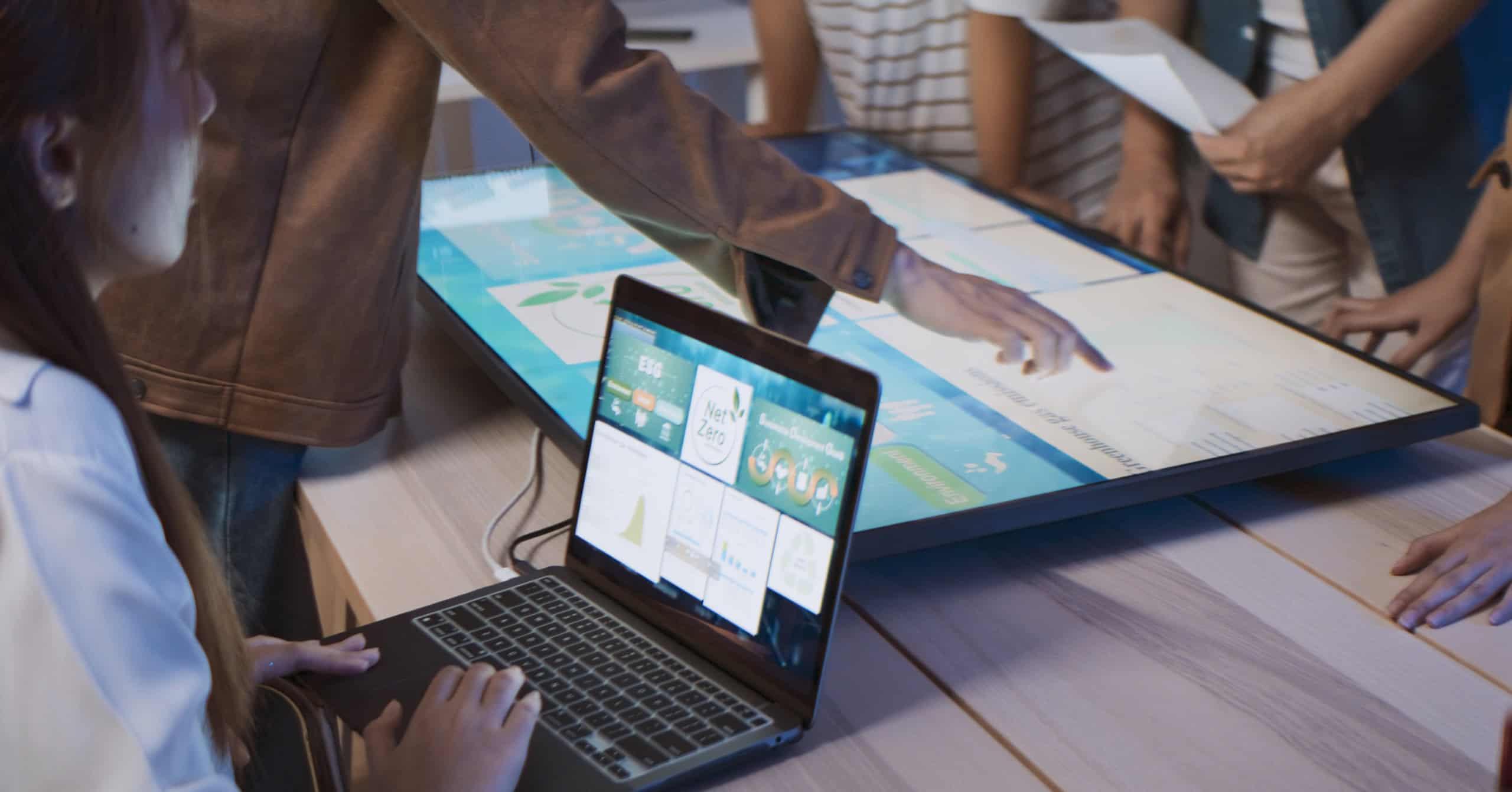 A person sitting at a desk with multiple screens, analyzing data or managing technology systems, emphasizing the role of innovation in facilities management.