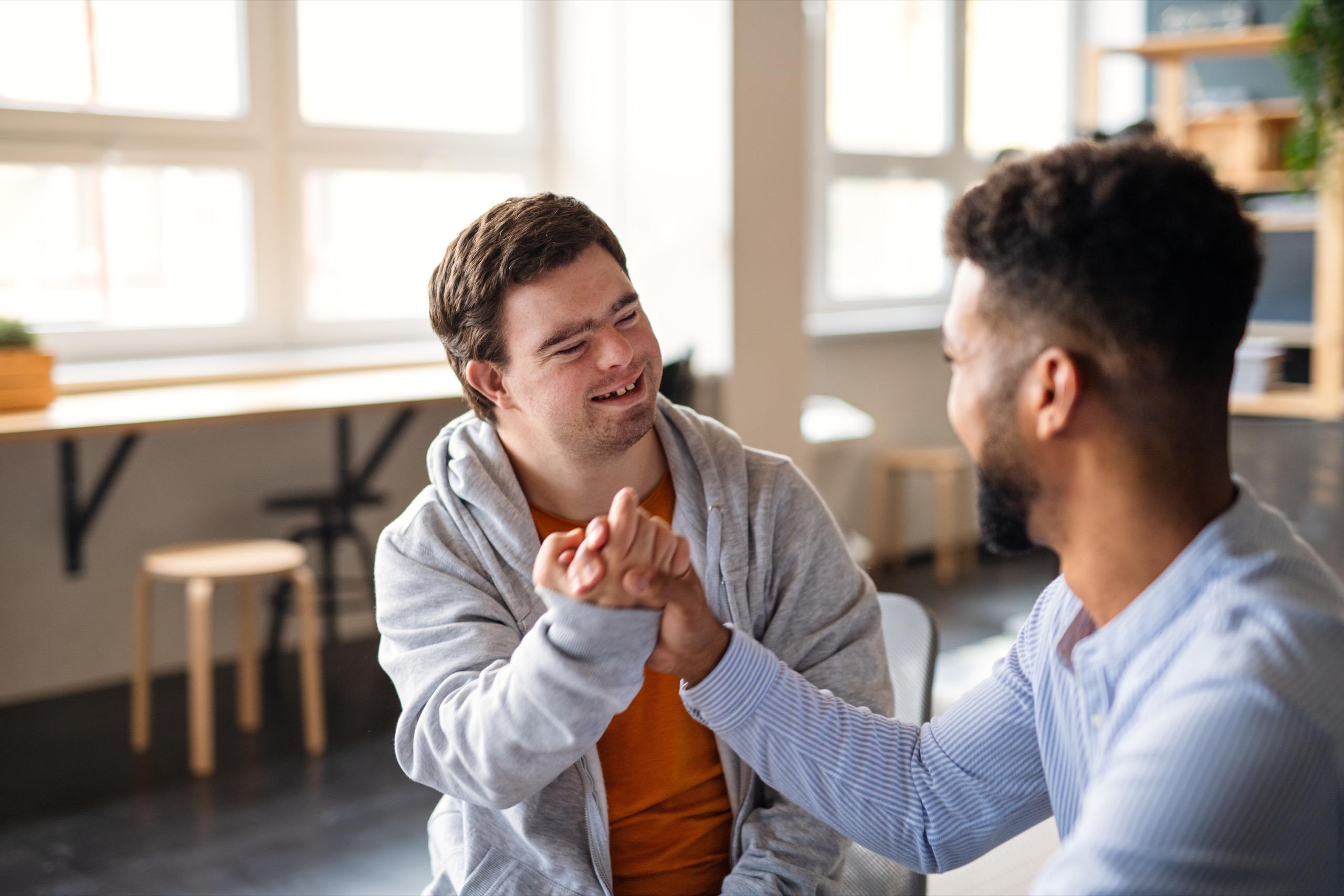 Two professionals smiling and shaking hands, engaged in a collaborative discussion, emphasizing partnership and trust.